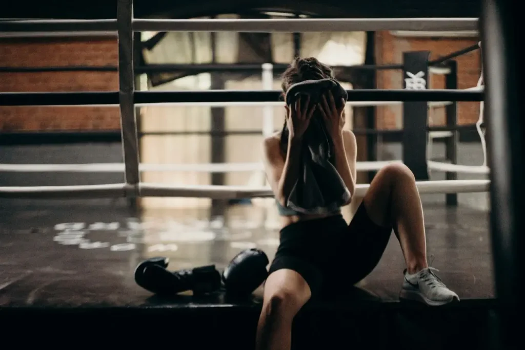 rapariga limpa o suor depois de um treino de boxe. Ela pensa que suar emagrece, mas é um mito. 