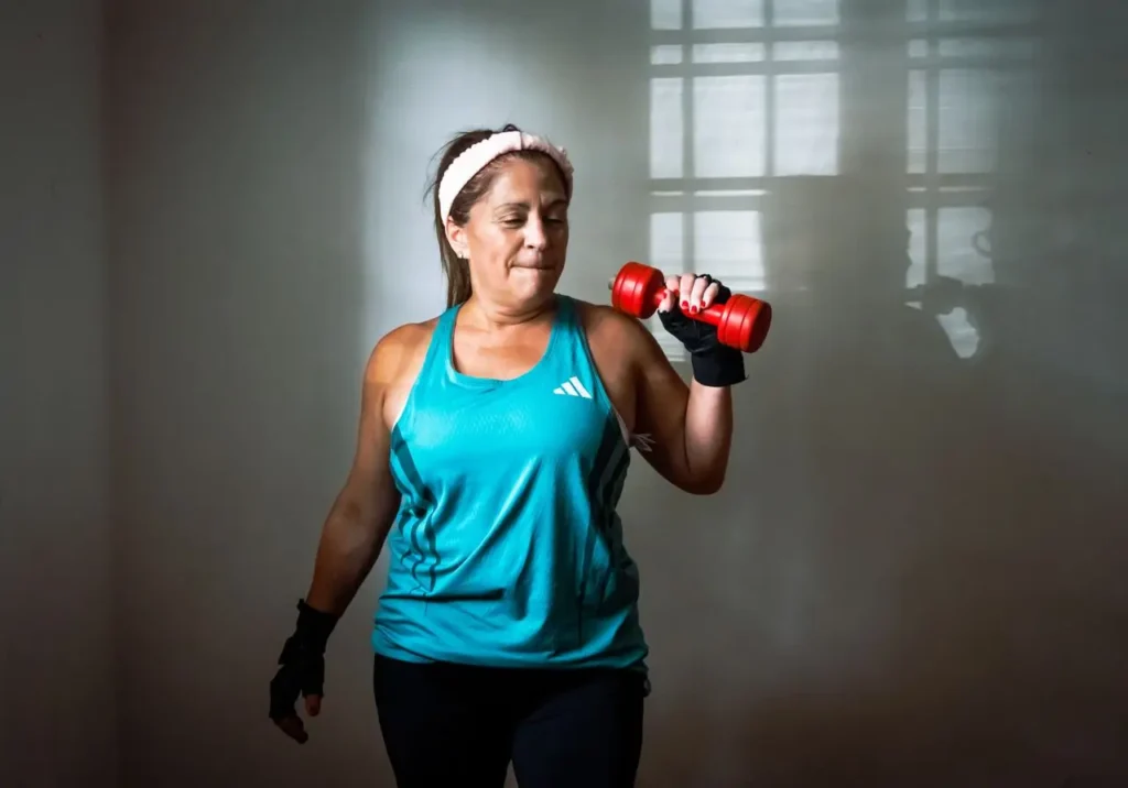 mulher treina em casa com haltere pequeno a treinar para emagrecer acompanhamento online BMFIT BodyMindFit