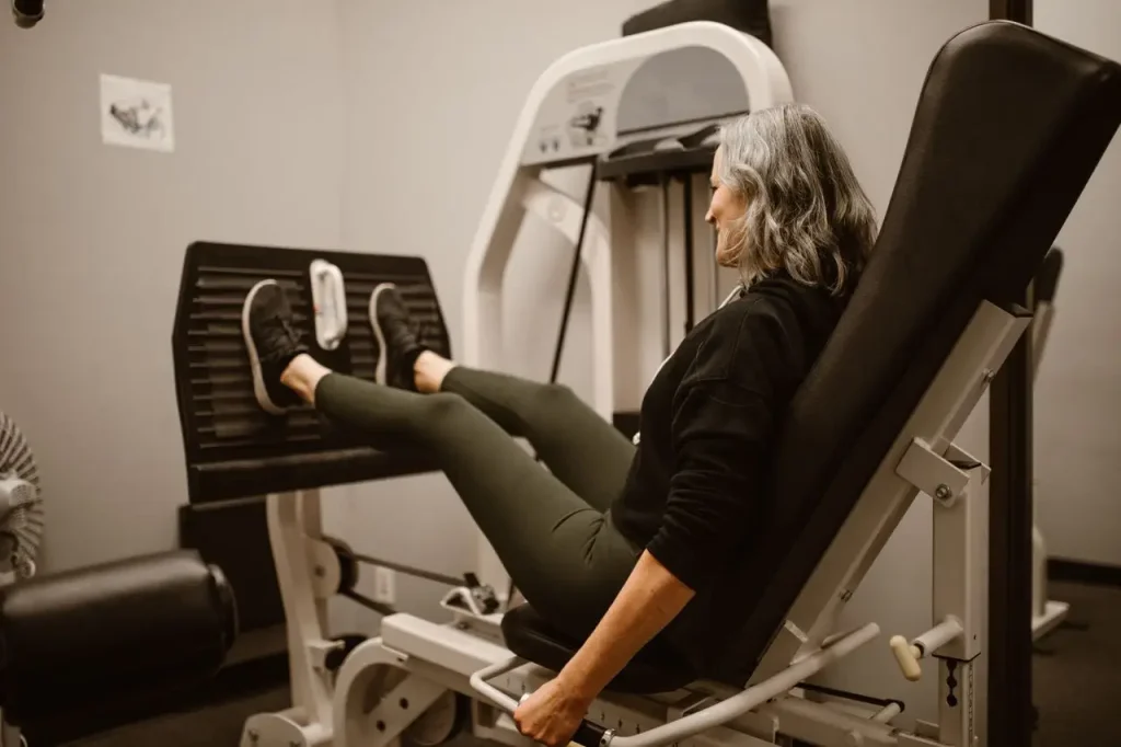 mulher treina no ginásio com leg press. Treinar em casa dá resultado mas o ginásio pode ser indicado para várias mulheres