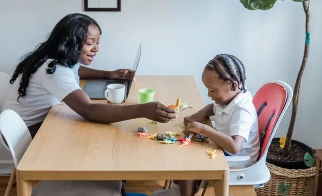 Mãe ocupada com trabalho e filho à mesa, sem tempo para comer, exemplo de fome física ligada à sensação de fome mesmo depois de comer