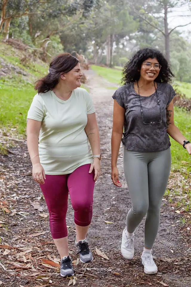 Duas amigas a caminhar e a sorrir, exemplo de ser influência positiva contra os sabotadores do emagrecimento