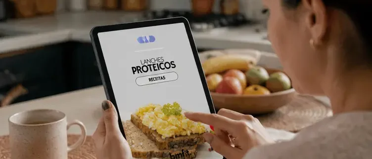 Mulher segura tablet com ebook de receitas de lanches saudáveis proteicos para emagrecer, elaborado por nutricionista especialista em menopausa Beatriz Jorge